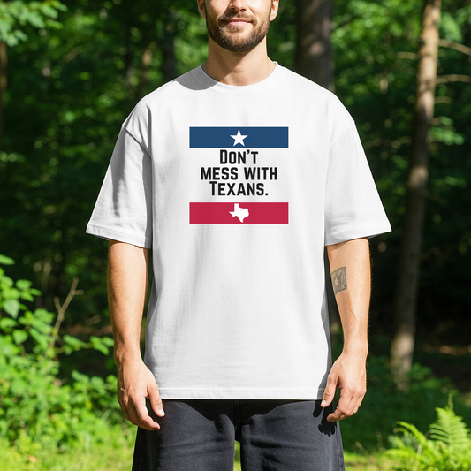 person standing outdoors wearing a white t-shirt with the text Dont Mess with Texans and red and blue graphic bars with a star and a small outline of the state of Texas.