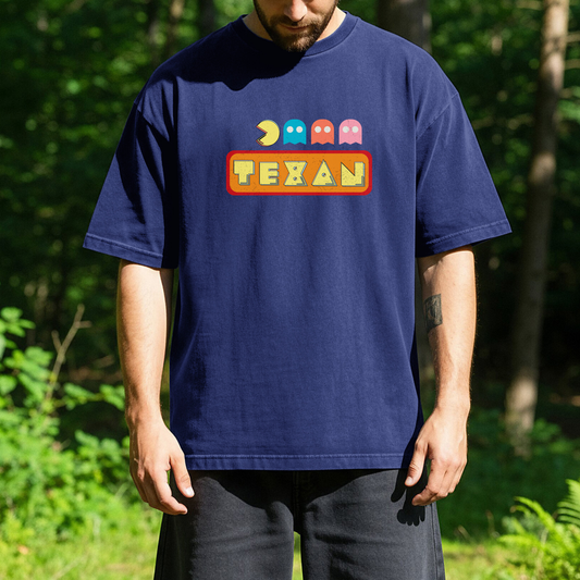 person standing outdoors wearing a blue t-shirt with a colorful graphic featuring a vintage video game style above the word Texan.